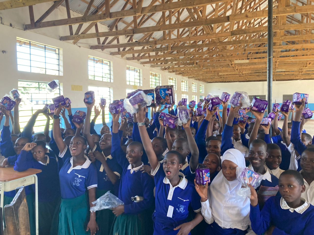 Students at Kafundo Secondary School raising packets of sanitary pads above their heads