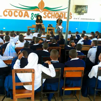 Students seated in the school hall listening to speakers at the front during a SheRooted visit