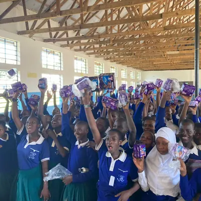 Students raising sanitary pad packets above their heads in the school assembly hall