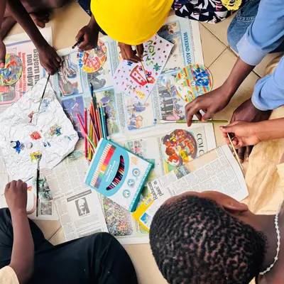 Children colouring pictures on sheets spread across the floor at Sintanaizer Foundation