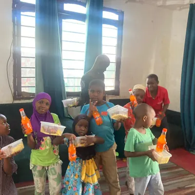 Children holding drinks and snacks handed out during a SheRooted visit to Sintanaizer Foundation